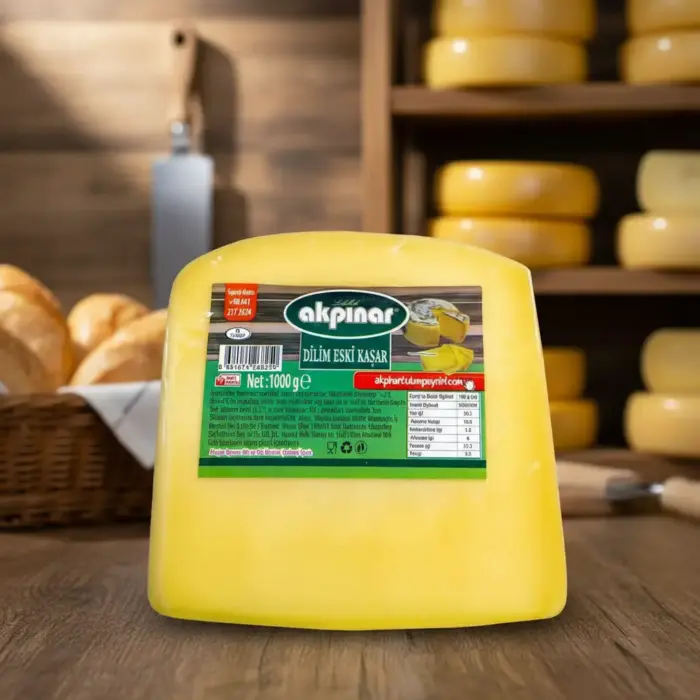 Akpınar Dilim Eski Kaşar Peyniri 1000 gr, peynir rafları ve ekmek sepeti önünde sunulan yakın plan ürün görseli.