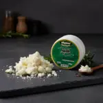 Siyah sunum taşında ufalanmış tulum peyniri ve arka planda Akpınar Erzincan Tulum Peyniri 450 gr ambalajı.